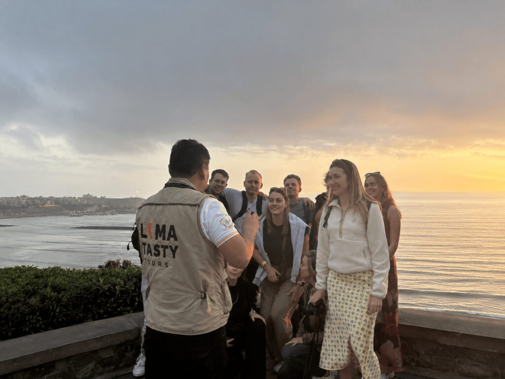 Is Lima food tour worth it? Certified local guide from Lima Tasty Tours sharing insights with a small group of international travelers during a walking culinary experience along the coast in Lima, Peru.⁠
