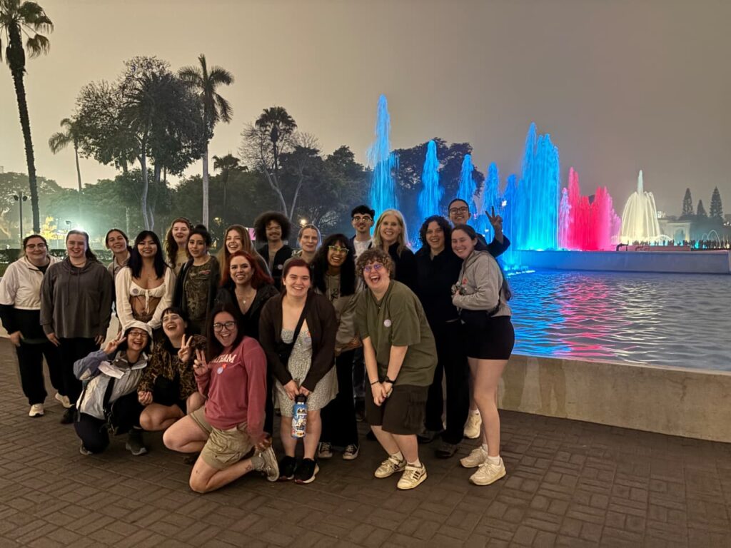 A large group of happy international travelers enjoying the illuminated fountains at the Magic Water Circuit during the Lima Tasty Tours evening culinary and history experience.⁠