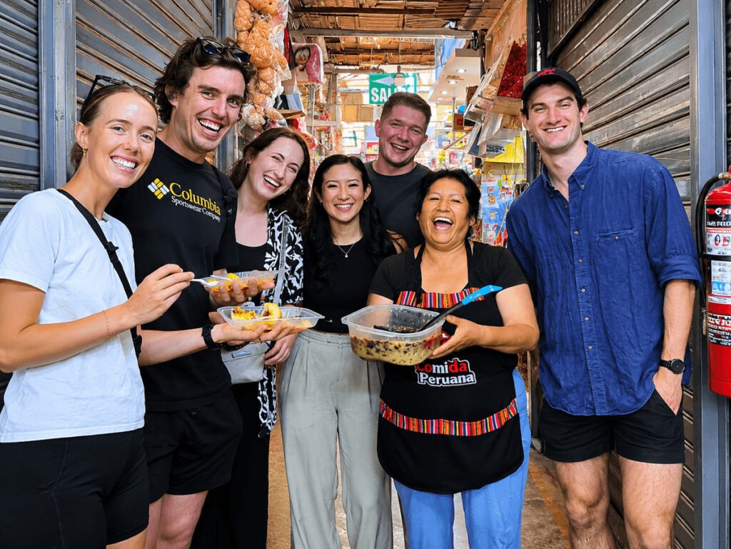 International foodies laughing and enjoying traditional Peruvian dishes with a local market cook during a Lima Tasty Tours culinary experience.⁠